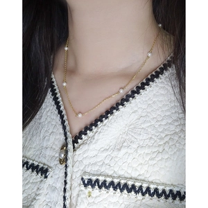 Minimalist gold S925 silver necklace with white pearls on a model in a tweed jacket