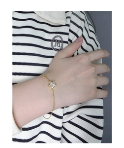 Close-up of a gold star charm bracelet with a sparkling zircon on a woman's wrist