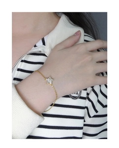 Close-up of a gold star snowflake bracelet with sparkling zircons on a woman's wrist