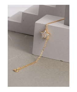 Close-up of a gold snowflake bracelet with zircon charms on a geometric stone