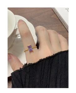 Close-up of a vintage-style gold rope ring with a rectangular purple gemstone