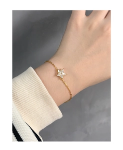 Detailed view of a gold snowflake bracelet with sparkling zircons on a woman's wrist