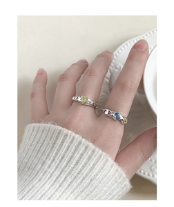 Detail of S925 silver rings with yellow star zircon and wavy blue stone on a hand