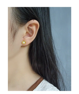 Close-up of S925 silver shell pearl stud earring on model with golden radiating texture