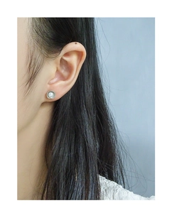 Detail view of S925 silver pearl stud earring with shell texture on model