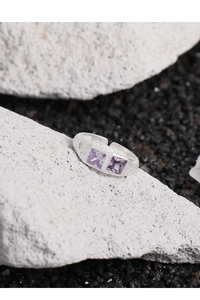 Vista macro di anello in argento S925 con trama grezza e zirconi viola quadrati