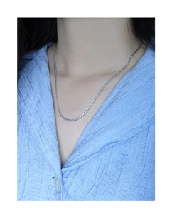 Nahaufnahme der minimalistischen S925 Sterlingsilber Schlangenkette auf hellblauem Hemd