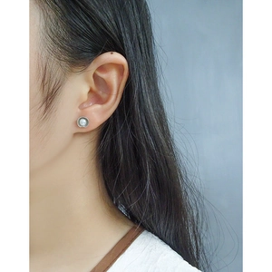 Classic round pearl stud earrings with textured silver rim on a model's ear