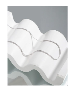Makroaufnahme einer silbernen flachen Schlangenkette auf minimalistischem weißem Stein