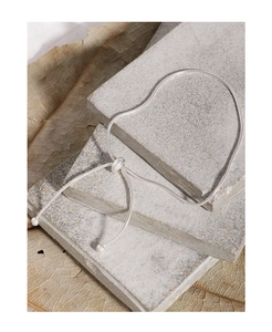 Detail of adjustable silver snake chain bracelet with sliding bolo clasp on stone background