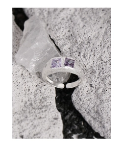 Dettaglio anello in argento S925 con trama irregolare e due zirconi viola quadrati