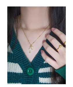 Model wearing gold cross pendant necklace and zircon ring over striped knitwear