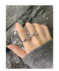 Detailed view of S925 silver rings with red heart and purple gems on a textured rock