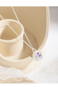 Detail of S925 silver necklace featuring a round pendant with three colored heart stones