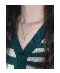 Close-up of golden double cross necklace with zircon stones worn by a model