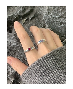 Macro detail of S925 silver rings with heart and star gems on grey rock texture