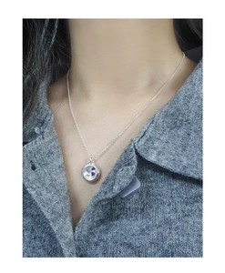 Close-up of S925 sterling silver necklace with a round locket pendant and colorful zircons