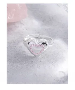 Détail d'une bague coeur en argent S925 avec pavé de zircons roses sur fond gris mat