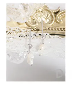 Close-up of S925 silver knot earrings with irregular pearls on elegant lace background