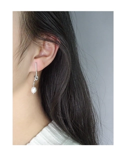Close-up of S925 silver knot earrings with dangling white pearls on a female model