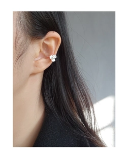 Detail view of a silver floral ear cuff with white petals and a central white pearl