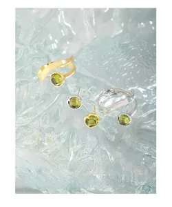 Detailed view of silver and gold wave rings with light green crystal stone settings
