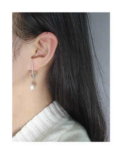 Detail of S925 silver knot earrings with a white pearl drop on model closeup