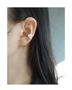 Detail of white flower ear cuff with central pearl on model, minimalist no-piercing design
