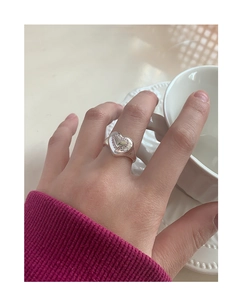 Détail de la bague coeur argentée avec zircons roses portée à la main au décor chic