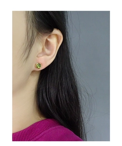 Gros plan d'une boucle d'oreille en cristal vert olive sur une base dorée
