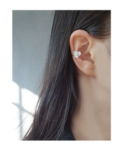 Close-up of a silver floral ear cuff with white enamel petals and a central pearl accent