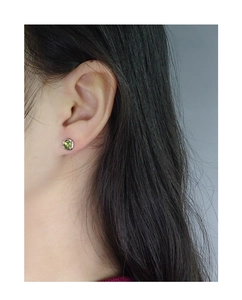 Gros plan de boucles d'oreilles en argent S925 avec cristal vert serti griffes sur l'oreille
