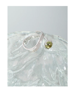 Macro detail of S925 silver irregular ring with prong-set green crystal on textured glass