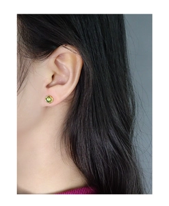 Gros plan d'une boucle d'oreille en argent S925 avec cristal vert serti à griffes