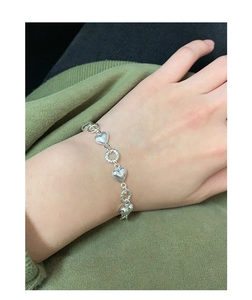Detailed view of S925 silver twist chain bracelet with heart charms on female wrist