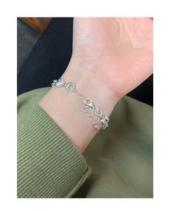 Detail view of S925 silver bracelet featuring heart charm and twisted ring on wrist