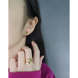 Modern gold double-layer ring and matching green gemstone stud earrings on model