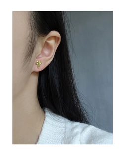 Detailed close-up of a golden leaf earring on ear, showing intricate vein textures