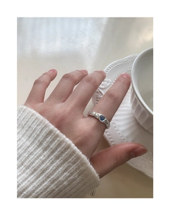Close-up of S925 silver heart ring with blue zircon on textured lava surface