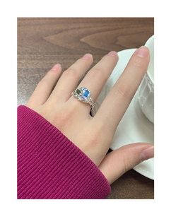 Détail d'une bague en argent à texture irrégulière et zircons colorés portés à la main