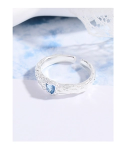 Macro shot of silver molten heart ring with blue zircon and hand-hammered texture