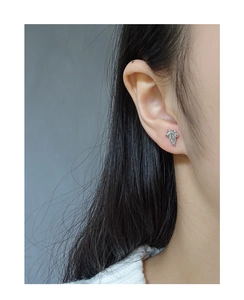 Detailed close-up of a silver-toned leaf stud earring worn on a female model's ear