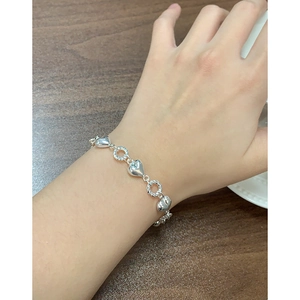 Elegant S925 sterling silver heart bracelet with twisted rings on woman's wrist
