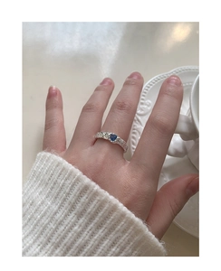 Detail of silver heart ring with blue zircon and irregular lava texture on hand