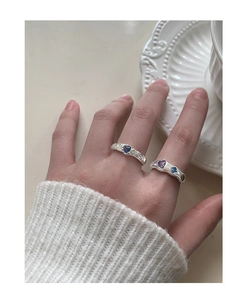 Detail of silver lava rings with heart-shaped zircon stones on hand with knit sweater