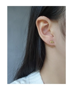 Close-up of a minimalist golden bird stud earring worn on ear for a refined look