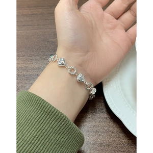 Elegant S925 sterling silver bracelet featuring polished hearts and twisted rings on a wrist