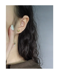 Detailed close-up of a golden spiral textured earring worn by a model in a side profile view