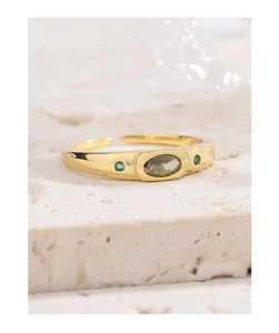 Detail of adjustable gold ring with oval green gemstones on natural stone surface