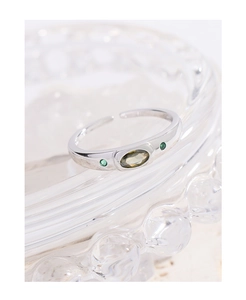 Macro shot of silver ring featuring oval olive green gemstone and tiny side stones